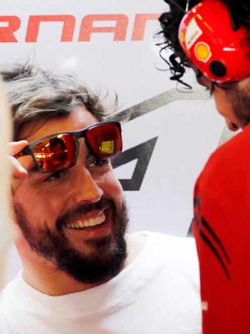 Fernando Alonso of Spain talks with Ferrari crew in the pit during a practice session for the Abu...