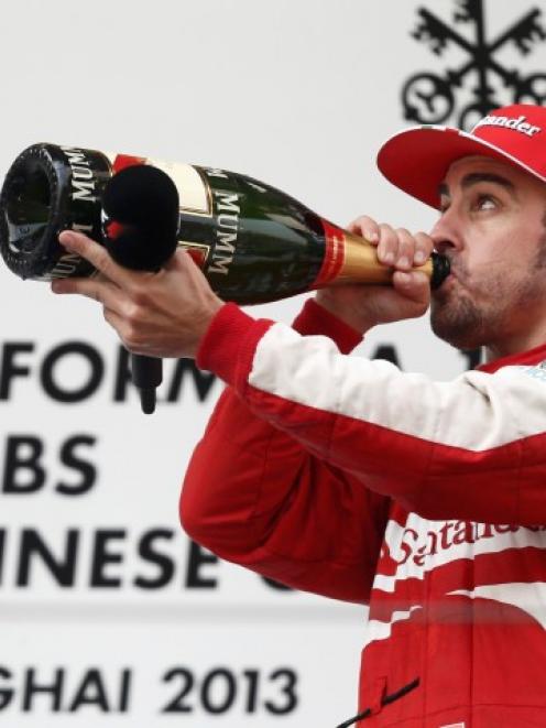 Ferrari driver Fernando Alonso of Spain drinks champagne as he celebrates winning the Chinese F1...