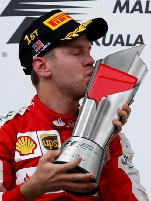 Ferrari's Sebastian Vettel celebrates with the trophy after winning the Malaysian Grand Prix....