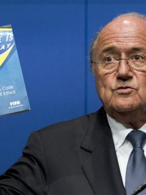 FIFA President Sepp Blatter holds the FIFA Code of Ethics while talking to the media during a...