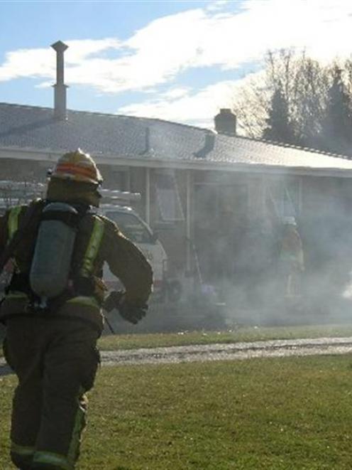 A firefighter runs towards 39 Marslin St in Alexandra with a hose at the ready during a midday...