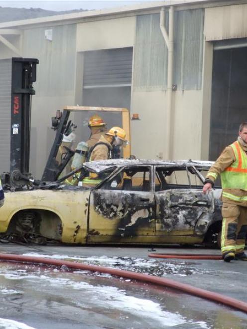 Fire crews used breathing apparatus while extinguishing a fire which started in this wrecked car ...