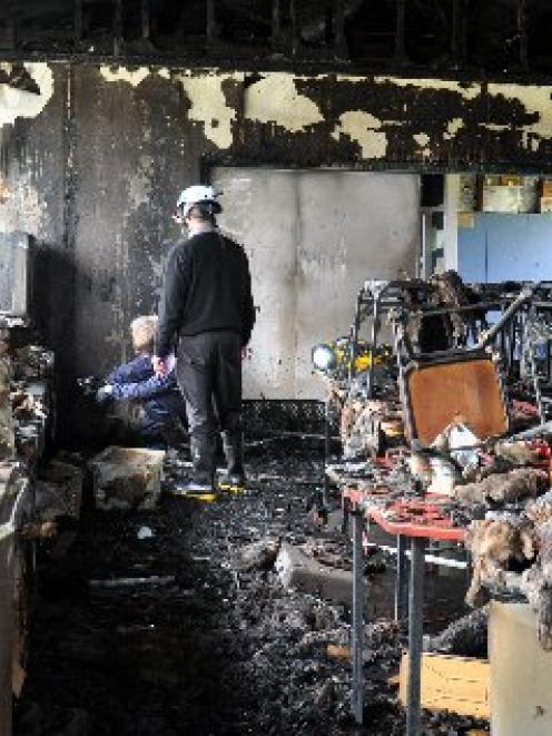 Fire investigators sift through the remains of a home economics room at South Westland Area...