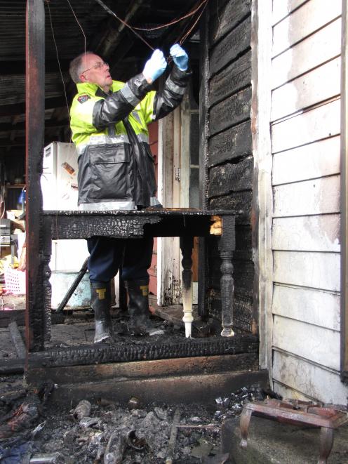 Fire safety officer Barry Gibson checks the wiring at a badly damaged house in Millers Flat after...