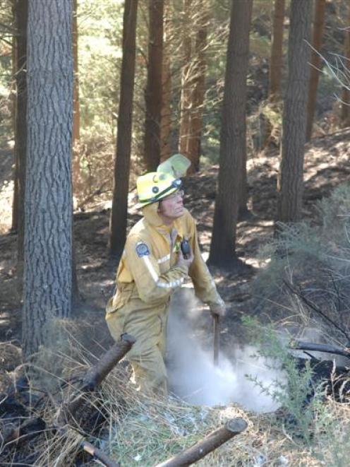 Firefighter James McCrorie digs up a "hot spot" left after fire ripped through Wenita's Mt Allan...