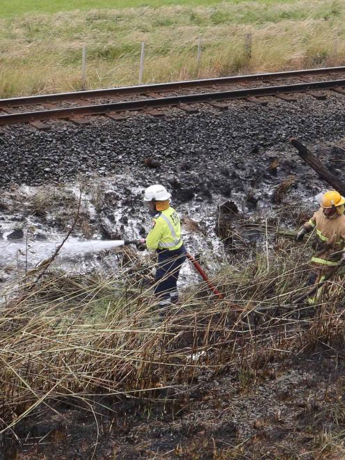 Firefighters dampen down a grass fire beside railway tracks near Henley. Photo by Craig Baxter.