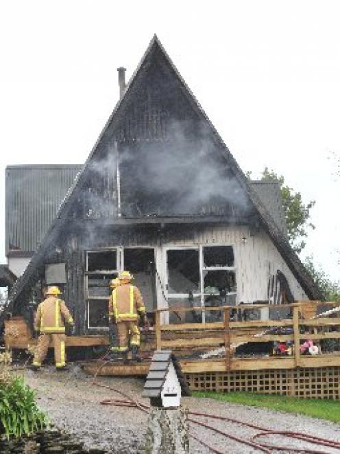 Firefighters dampen down a Waikouaiti home gutted by fire yesterday. Photo by Linda Robertson.