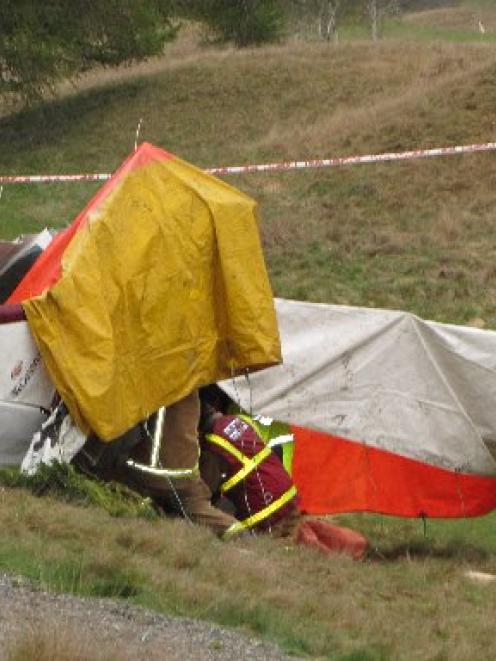 Firefighters examine the broken fuselage of the Cessna Skyhawk which crashed on the Arrowtown...