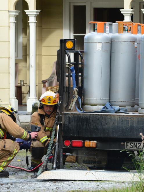 Firefighters monitor the temperature under an LPG delivery truck after it caught fire in Great...