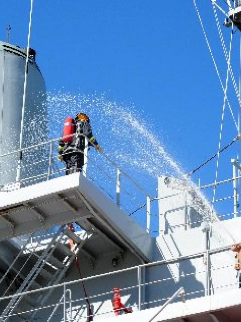 Firefighters pour water on an imaginary fire on board HMNZS Endeavour during an exercise in...