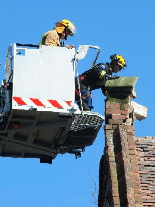 Firefighters remove loose bricks from the top of a Christchurch heritage building. Photo by Craig...