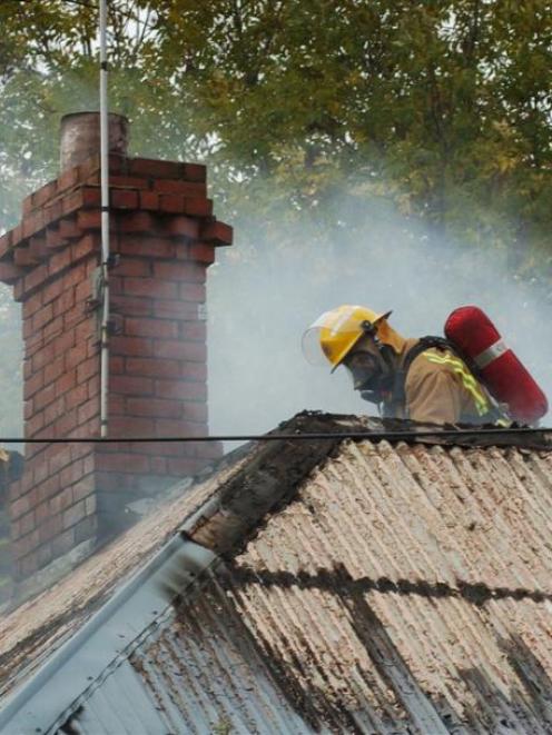 Firefighters strip iron from the roof of a burning house in Chambers St, Northeast Valley, on...