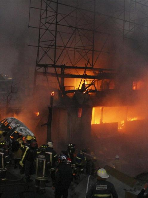 Firefighters try to extinguish a fire caused by the explosion of a gas tanker truck in San Pedro...