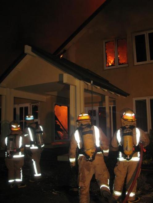 Firefighters try to save the Crown Terrace home last night. Photo by Dave Cannan.