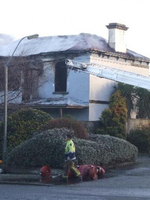 Firefighters work on the remains of the Road Knights' Invercargill headquarters destroyed in a...