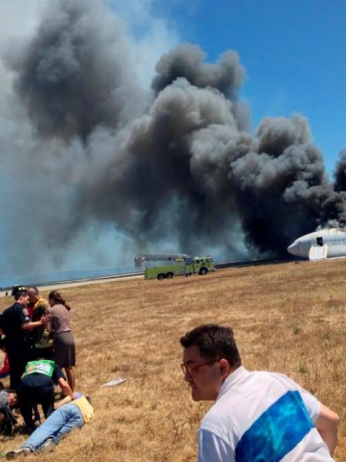 First responders tend to Asiana Airlines flight attendants and rescued passengers as they gather...