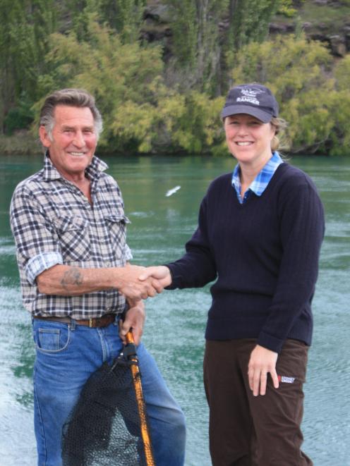 Fish and Game officer Clare Morris (right)  presents a catch net to  Ken Leckie,  who has been...