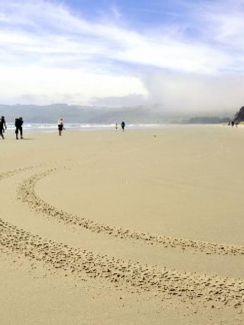 Fishermen walk back to their cribs at Long Beach following a morning of spear fishing near the...