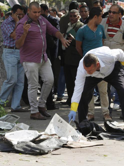 Forensic workers and policemen carry out investigations at the scene of a bomb blast in Cairo...