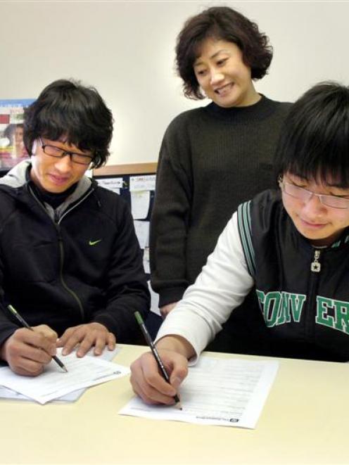 Francesca Shin assists Korean students Lee Deokjae (25), left, and Nick Yu (15) with opening bank...