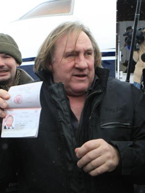 French film star Gerard Depardieu shows his new Russian passport after arriving at the airport in...