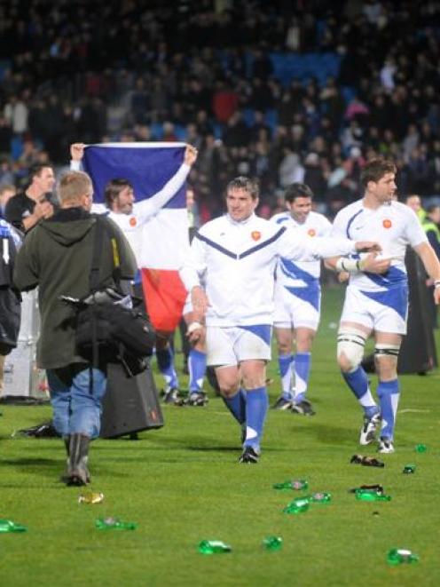 French players walk over a part of Carisbrook littered with bottles after Saturday night's test...