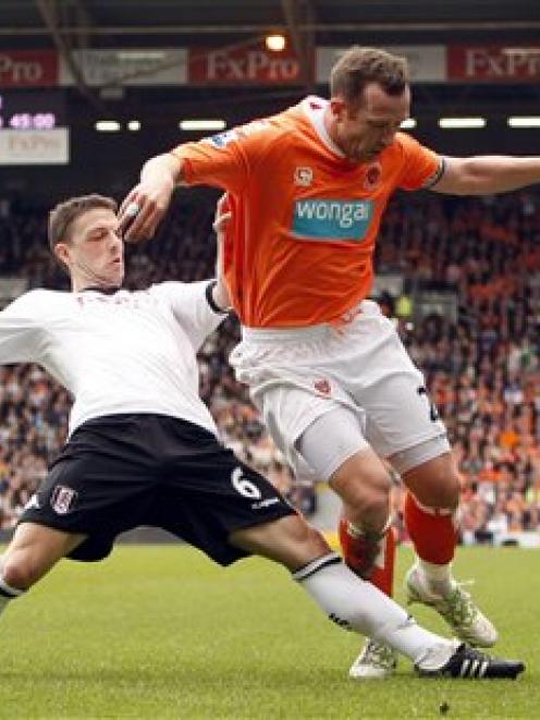 Fulham's Chris Baird, left, goes for the ball with Blackpool's Charlie Adam during their English...