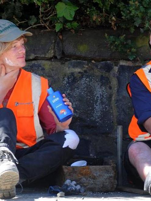 Fulton Hogan workers Nathan Waters (left) applies sunscreen during an afternoon break with fellow...