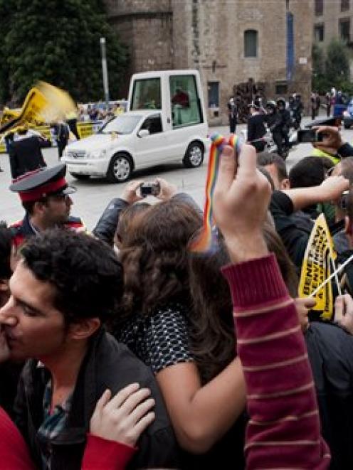 Gay activists kiss during a protest as Pope Benedit XVI passes by on his popemobile on his way to...