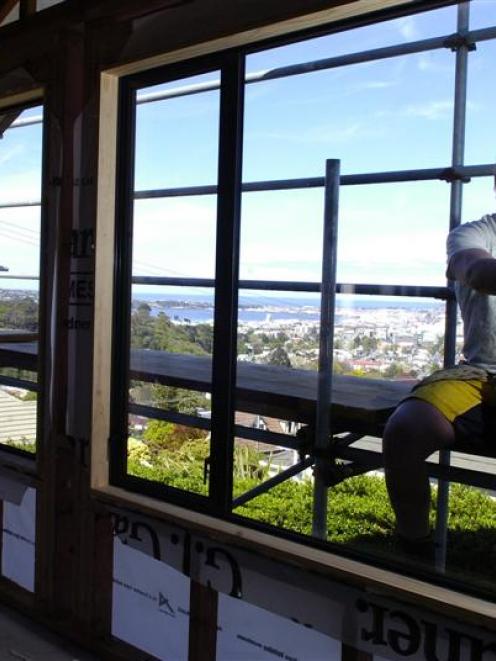 GJ Gardner Homes Otago apprentice builder Jason Bint installs a window at a new house on Pine...