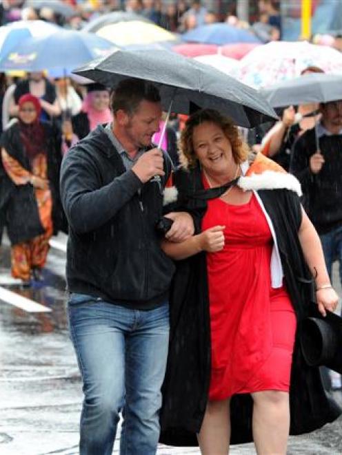 Graduate Jackie Gibson is sheltered under an umbrella by her brother Nigel Rook during a wet...