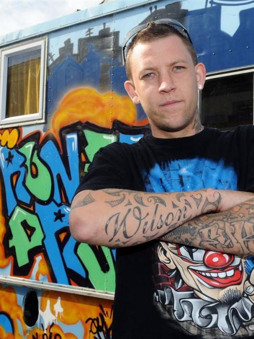 Graffiti artist Hunter Wilson with a mural he painted for Peter Hughes' bus, in Dunedin yesterday...