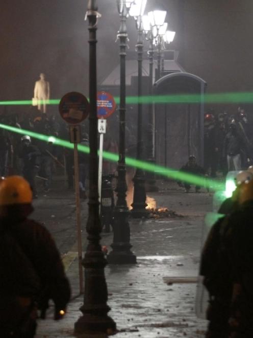 Green laser pointers are aimed at riot police by demonstrators during violent protests in central...