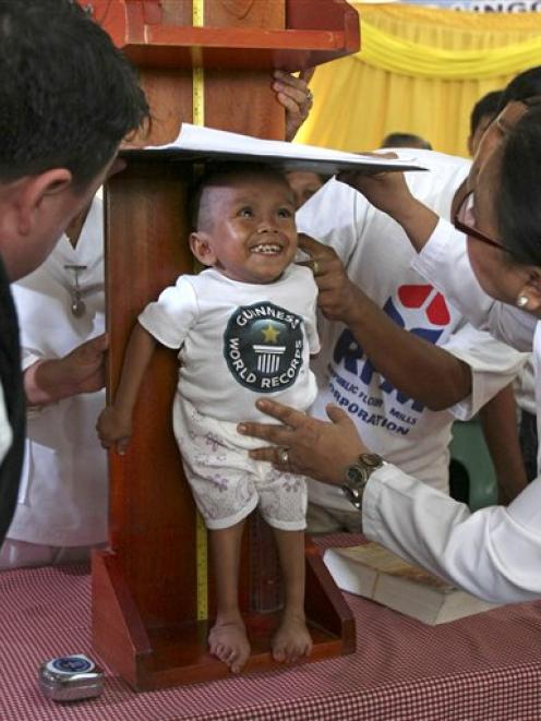 Guinness World Records adjudicator Craig Glenday, left, watches as Junrey Balawing is measured at...
