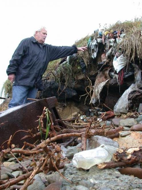 Hampden resident Bent Jansen examines rubbish exposed by coastal erosion of the Hampden dump....