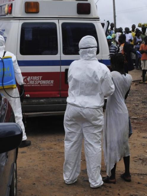 Health workers bring a woman suspected of having contracted Ebola virus to an ambulance in front...