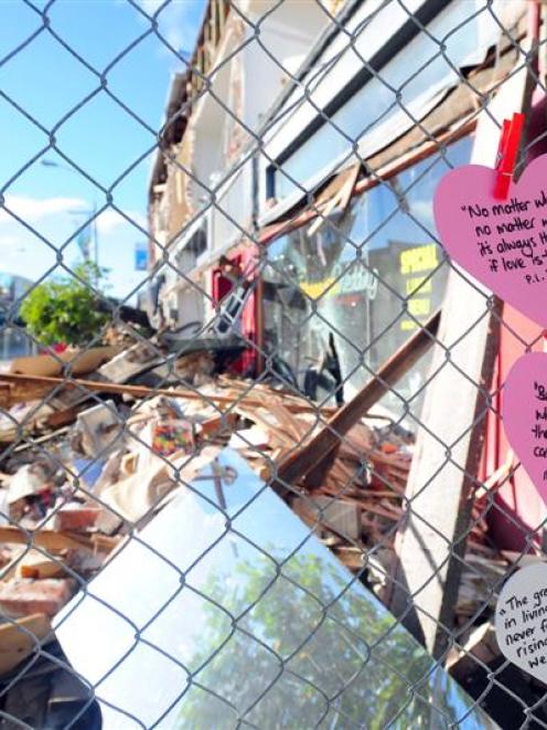 Heart-shaped cards with inspirational messages have popped up on fences around rubble sites in...