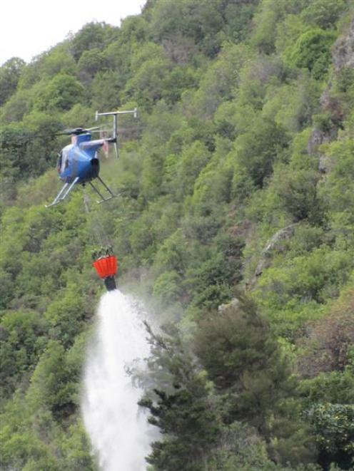Helicopter pilot Harvey Hutton drops water on to a slip near Makarora.