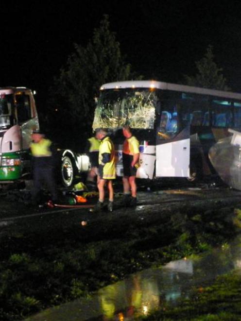 Helpers attend the accident scene after a dairy tanker and bus collided near Mataura last night....