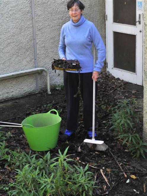 High Street School neighbour Margie Harris clears leaves and weeds from an entrance to the former...