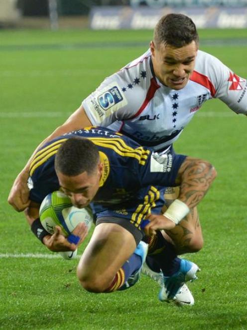 Highlanders halfback Aaron Smith goes over to score a try in the tackle of Rebels centre Tamati...