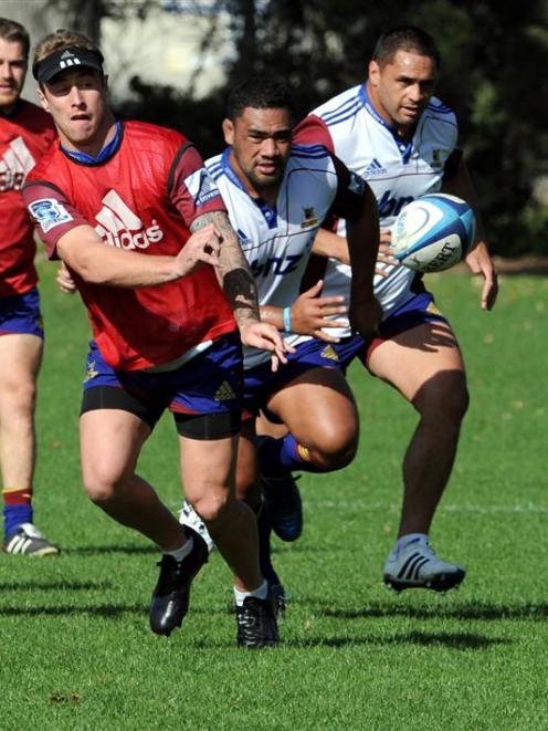 Highlanders halfback Jimmy Cowan passes the ball, while looking on are (from left) Brayden...