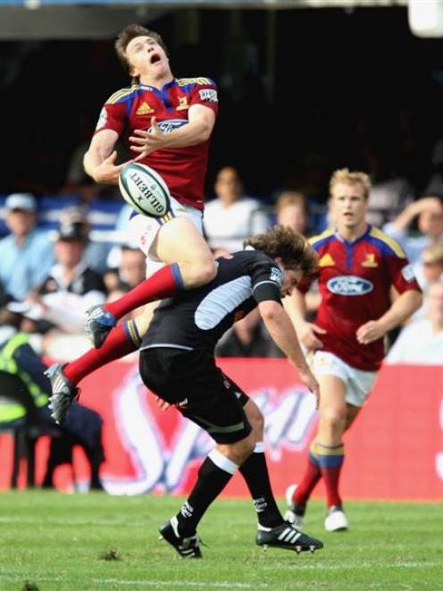 Highlanders winger Ben Smith goes high for the ball and lands on Francois Steyn, of the Sharks,...