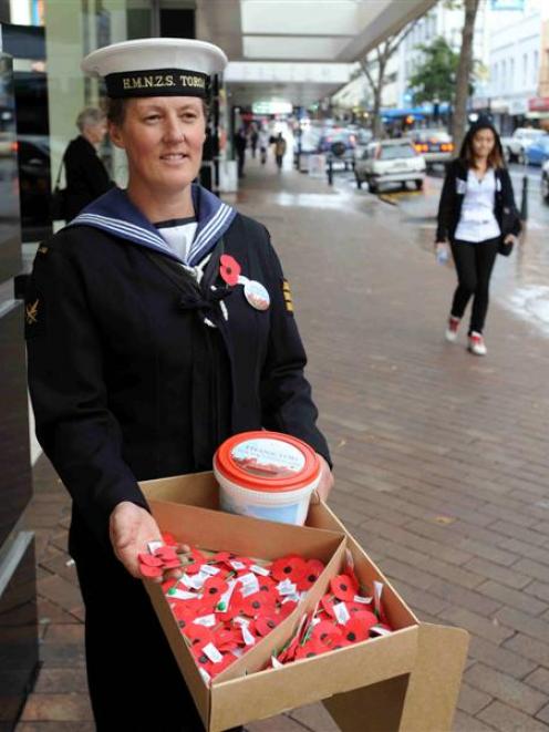 HMNZS Toroa naval reserve able writer volunteer Karen Robertson swaps poppies for cash during the...