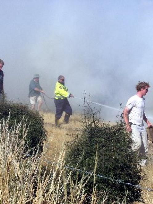 Hot work ... Firefighters dampen down hot spots after a fire near Millers Flat yesterday...