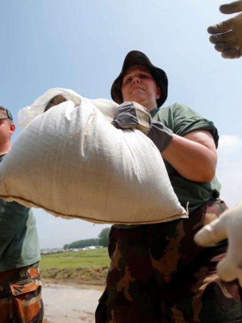 Hungarian soldiers prepare sandbags to help reinforce a dike along the swollen Danube River near...