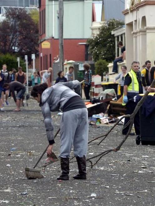 Hyde St resident Faith Van Lith sweeps up on Sunday while Hillary Palmer (19) carries a branch....
