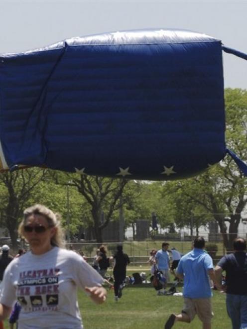 Participants in a New York soccer tournament run from an airborne inflatable "bounce house" after...