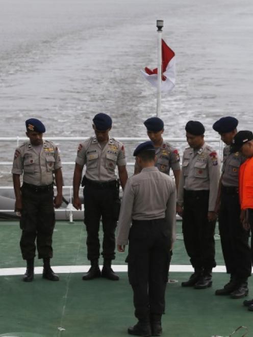 Indonesia policemen pray on deck of SAR ship KN Purworejo during a search operation for...