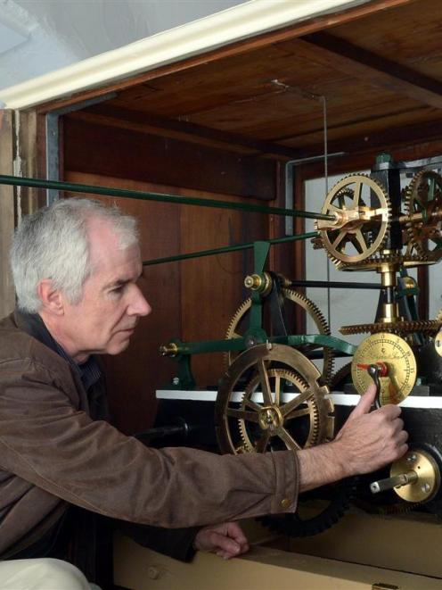 Inside Iona Church's clock tower yesterday, horologist Jeff Martin synchronises  the 1885 Little...